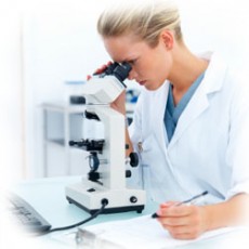 Female researcher looking into a microscope and writing notes at